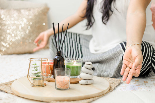 woman meditating at home in living room in front of wellness products