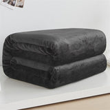 neatly folded black coral fleece blanket on white shelf