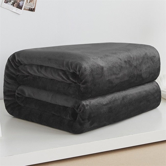 neatly folded black coral fleece blanket on white shelf