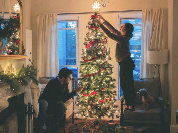 two people decorating home with christmas decor in living room