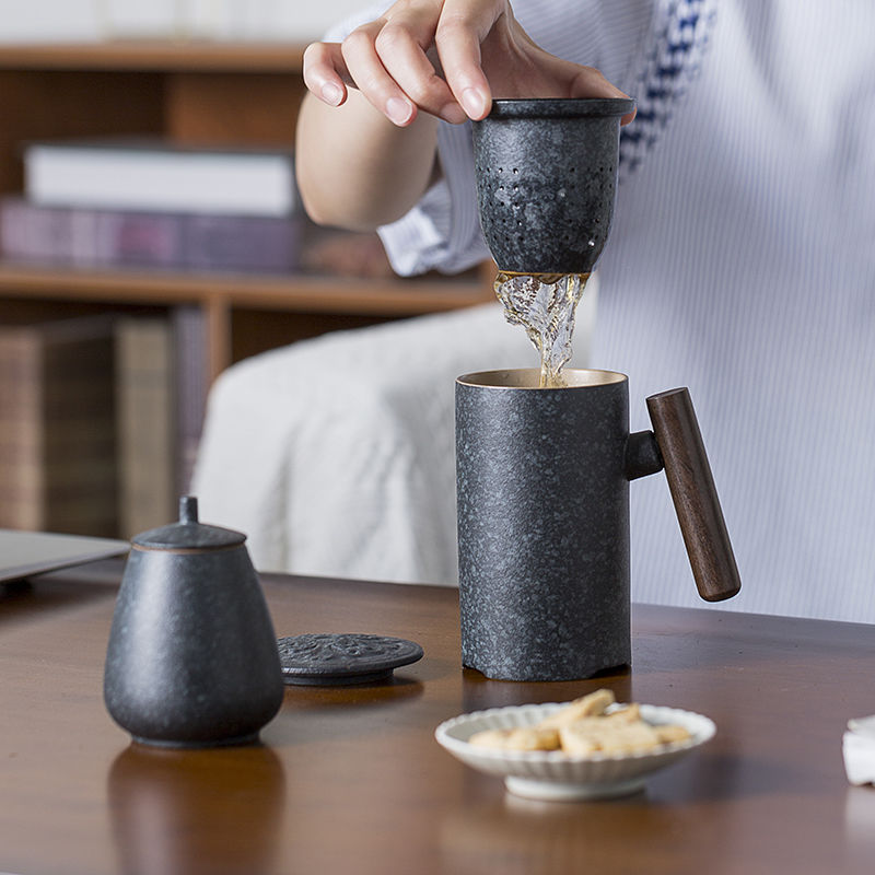person lifting tea infuser from ceramic tea mug to remove tea leaves