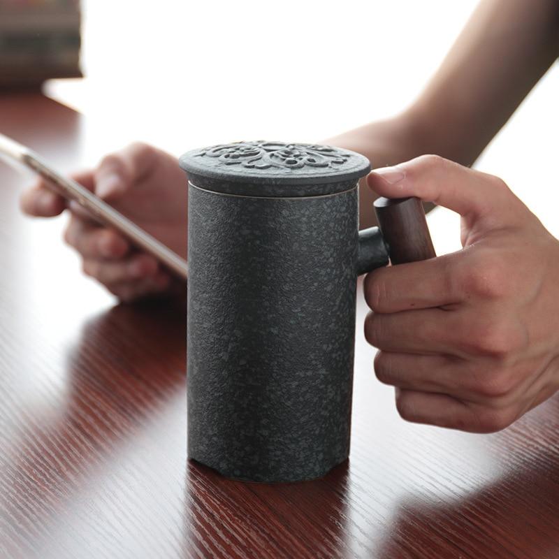 left hand holding ceramic tea mug with infuser