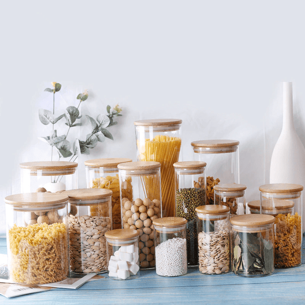 glass dry storage jars with wooden lids in various sizes on table