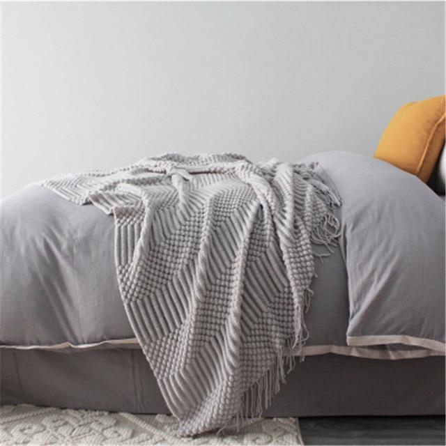 light gray knitted sofa throw used as light blanket in bedroom