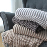 knitted sofa throw in light gray, smokey gray, and khaki on sofa chair