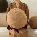 coal and cove tan round throw pillow being held by woman in pajamas