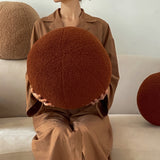 lady holding cinnamon colored round throw pillow with wool lining