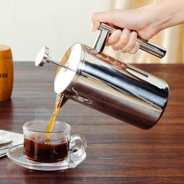 hand pouring coffee into cup with stainless steel french press