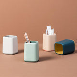 four pen holders with dual color minimalist design on brown backdrop
