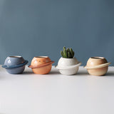 four small ceramic planets for succulents lined up against wall