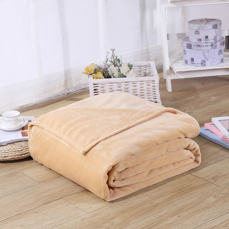 lightweight beige coral fleece blanket folded up on bedroom floor